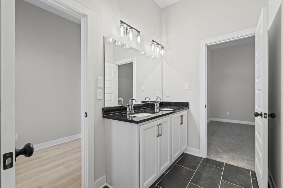 Full bathroom with double vanity and dark tile patterned flooring