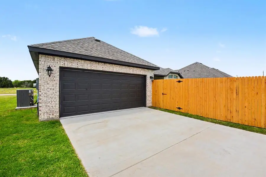 Attached garage with a dark sectional door, light brick exterior, and a dark shingle roof Attached garage with a dark sectional door, light brick exterior, and a dark shingle roof