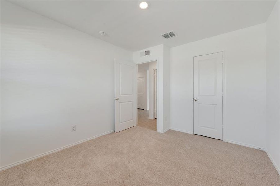 Unfurnished bedroom featuring light carpet and a closet