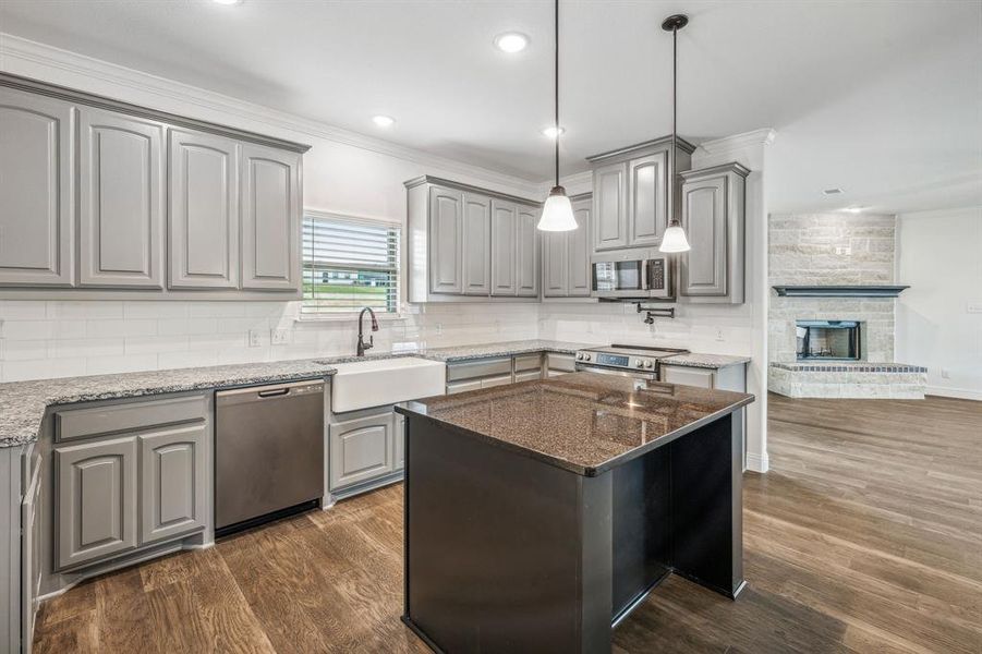 Kitchen with a stone fireplace, sink, dark hardwood / wood-style floors, and stainless steel appliances