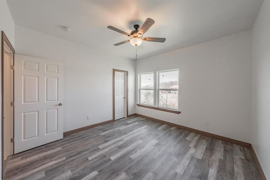 Unfurnished bedroom featuring a ceiling fan, a closet, baseboards, and wood finished floors