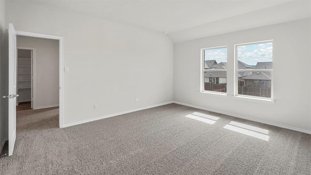 This room features light gray carpet flooring, two windows providing natural light, and a white door leading to a closet with built-in shelving