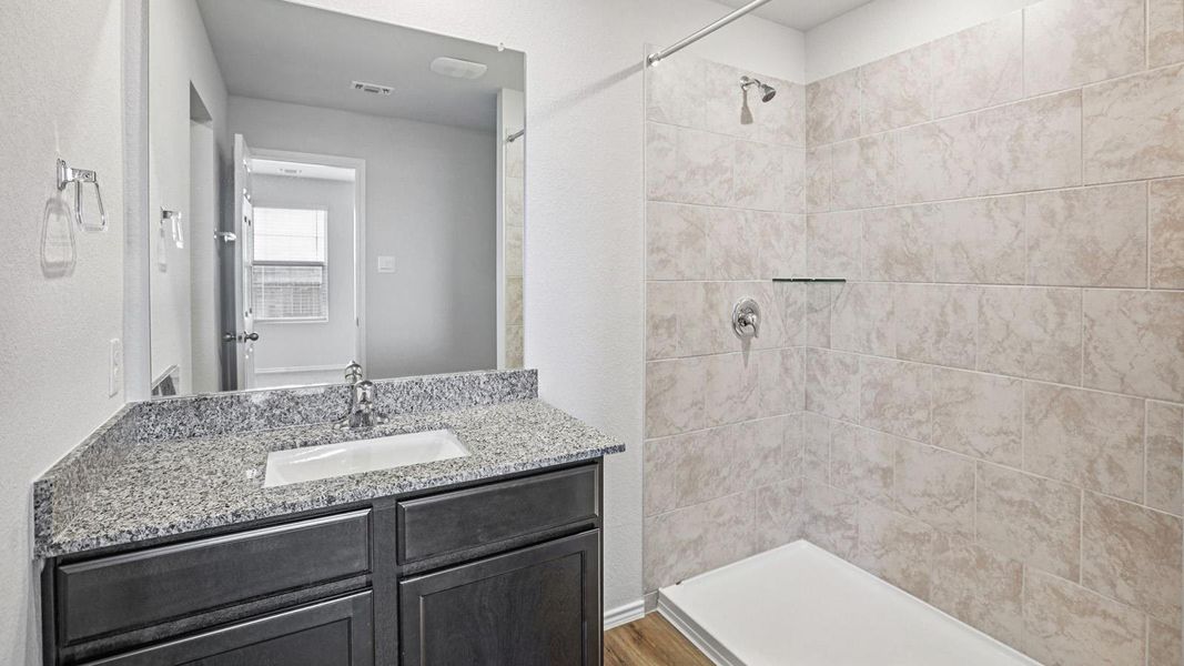 Granite counters and tiled shower elevate this contemporary bathroom space.