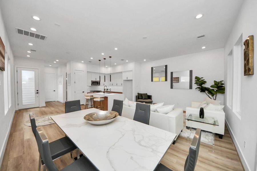 Discover a sleek, open-concept dining area seamlessly connected to a modern kitchen and cozy living space, perfect for entertaining and everyday comfort.