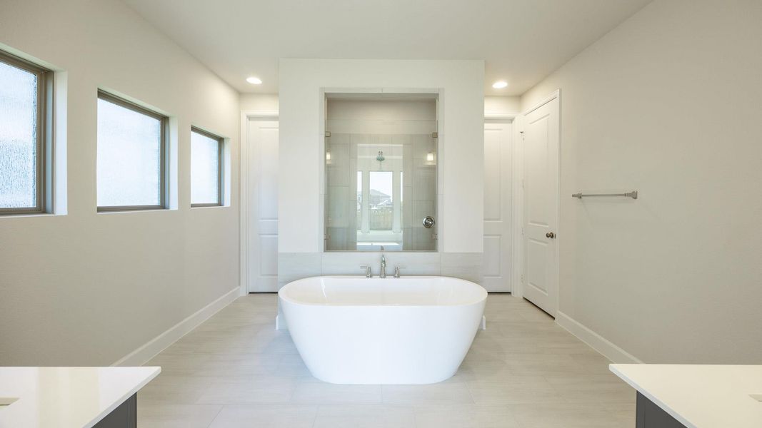 Bathroom featuring vanity, a shower stall, a freestanding tub, and light tile patterned floors