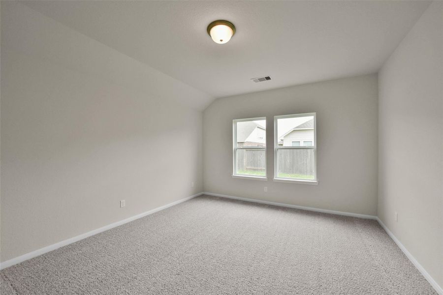 This room offers a spacious, neutral-toned interior with plush carpeting and ample natural light from two large windows. Ideal for a bedroom or home office.