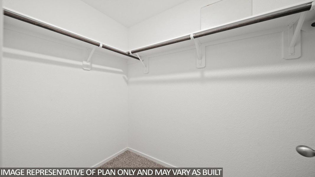 Walk-in closet with textured white walls, a corner configuration, and wall-mounted metal hanging rods
