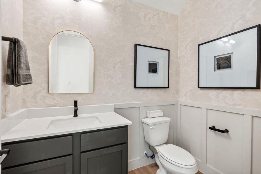 Downstairs powder room gleams with clean lines, decorative wall detailing and creates a welcoming space for guests