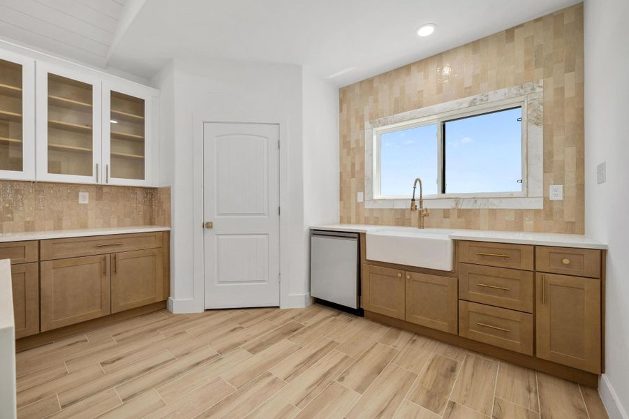 Kitchen with decorative backsplash, brown cabinets, glass insert cabinets, dishwasher, and recessed lighting Kitchen with decorative backsplash, brown cabinets, glass insert cabinets, dishwasher, and recessed lighting