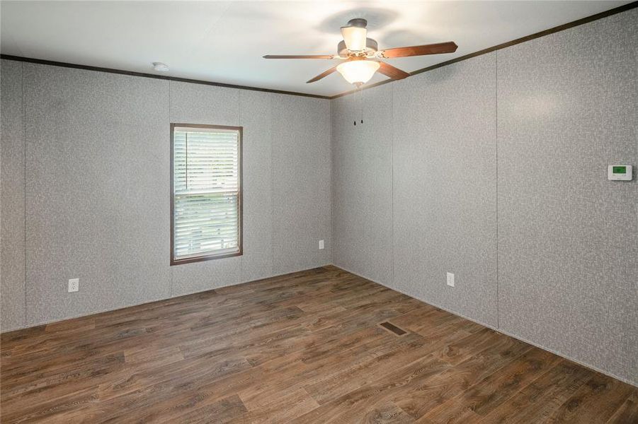 Unfurnished room featuring wood finished floors, ornamental molding, and a ceiling fan