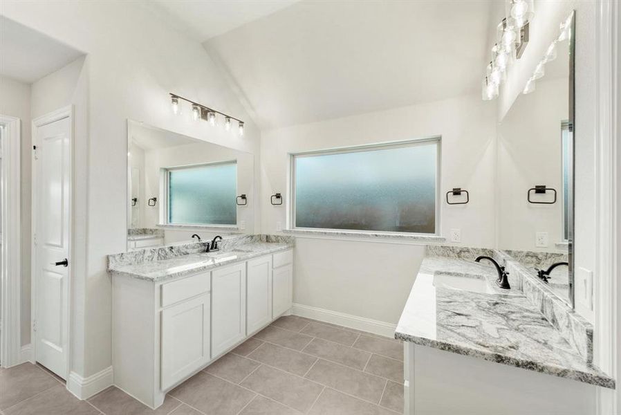 Spacious bathroom featuring dual vanities with white cabinetry, granite countertops, and undermount sinks Spacious bathroom featuring dual vanities with white cabinetry, granite countertops, and undermount sinks