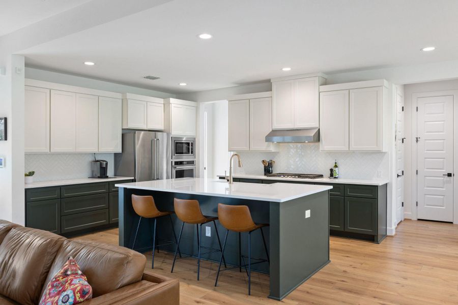 Kitchen with white cabinets, recessed lighting, a breakfast bar, decorative backsplash, and an island with sink