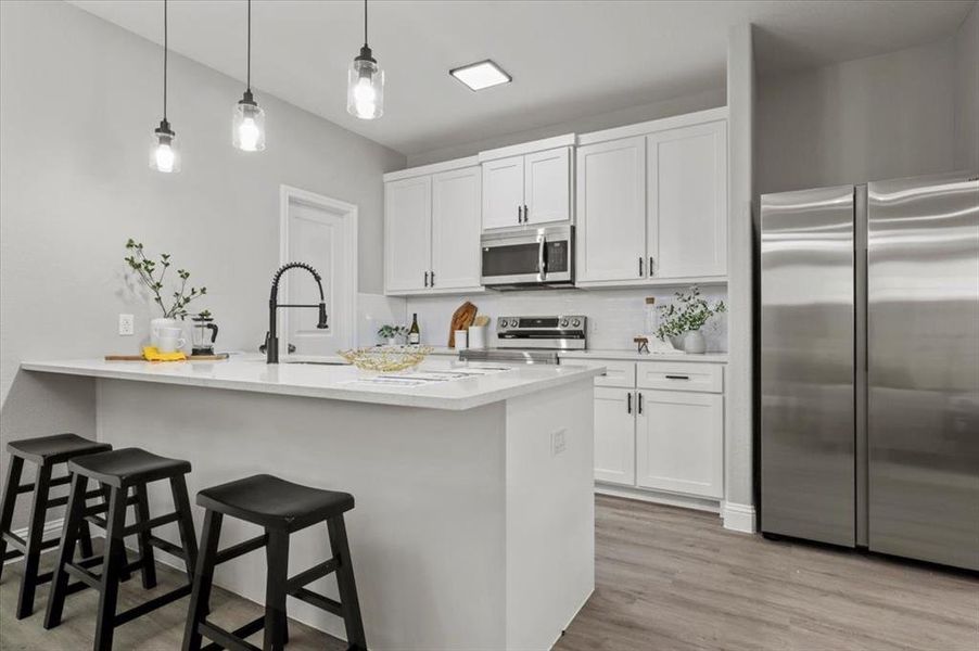 Kitchen featuring backsplash, a breakfast bar, white cabinets, and stainless steel appliances