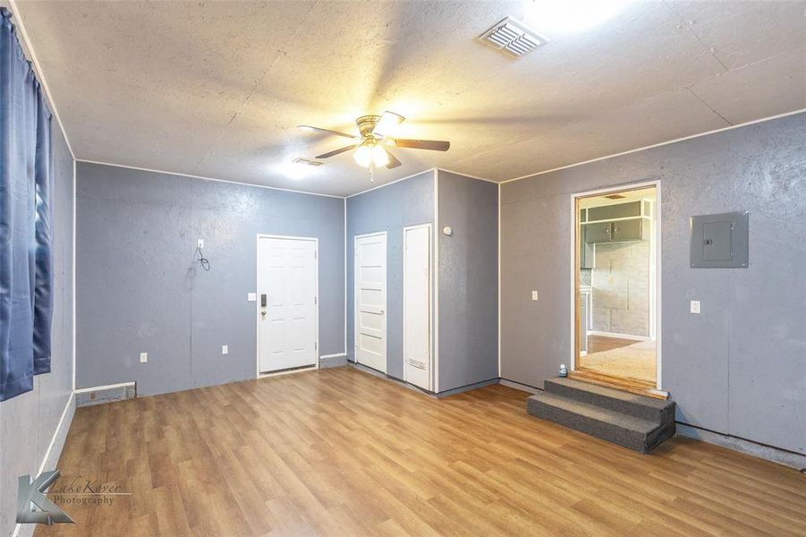Unfurnished room with wood finished floors, electric panel, ceiling fan, and a textured ceiling