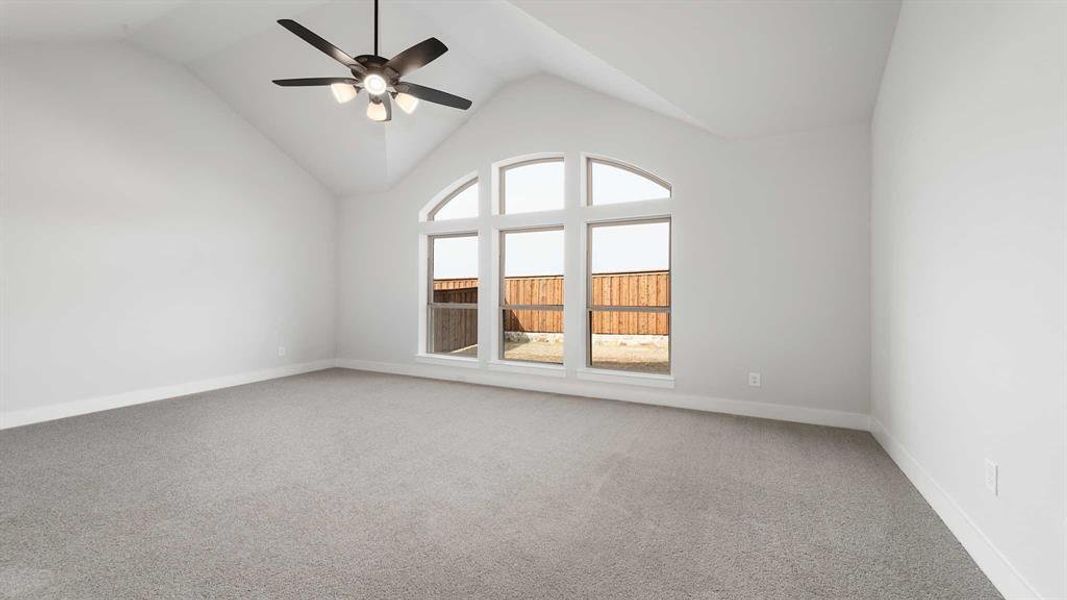 Spare room featuring vaulted ceiling, ceiling fan, and carpet