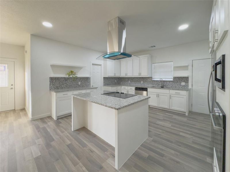 Kitchen with white cabinetry, sink, light hardwood / wood-style floors, and extractor fan