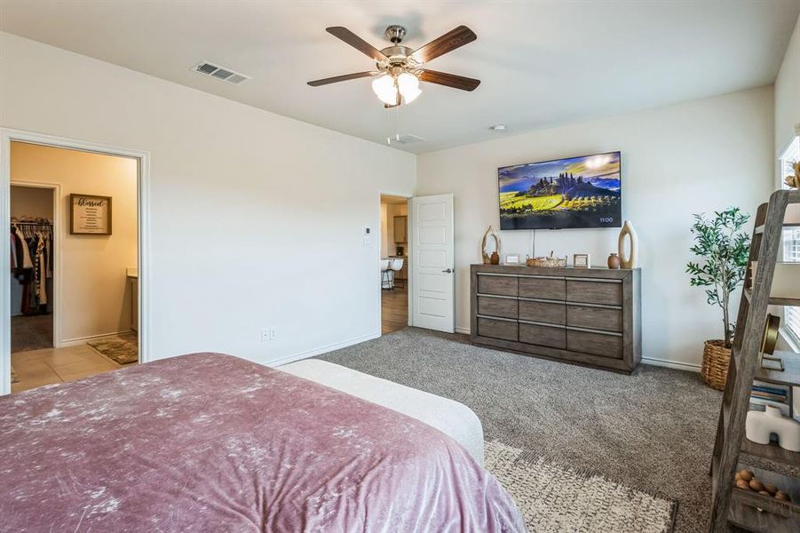 Carpeted bedroom featuring ceiling fan, a closet, and a walk in closet