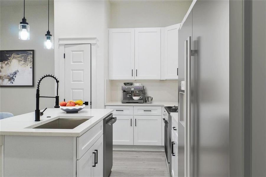 Kitchen with white cabinetry, pendant lighting, a center island with sink, and light countertops