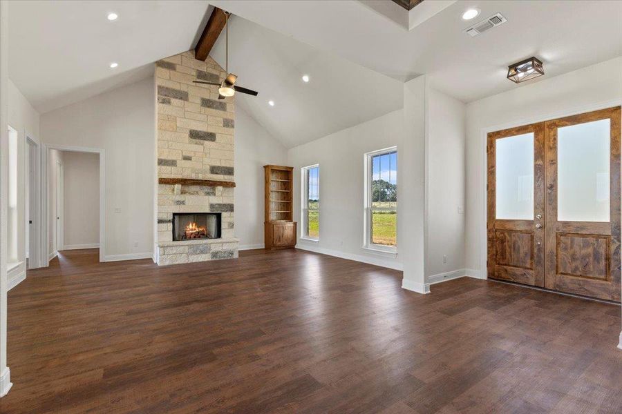 Foyer entrance featuring ceiling fan, high vaulted ceiling, a fireplace, beamed ceiling, and dark wood-style floors