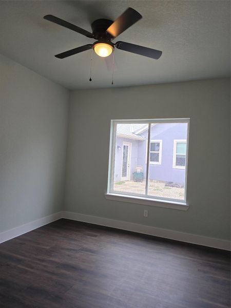 Spare room featuring dark wood-style flooring and a ceiling fan