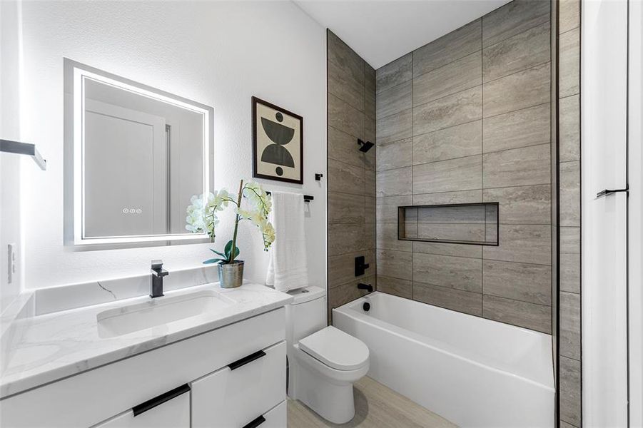 Bathroom featuring bathtub / shower combination, vanity, and light wood finished floors Bathroom featuring bathtub / shower combination, vanity, and light wood finished floors