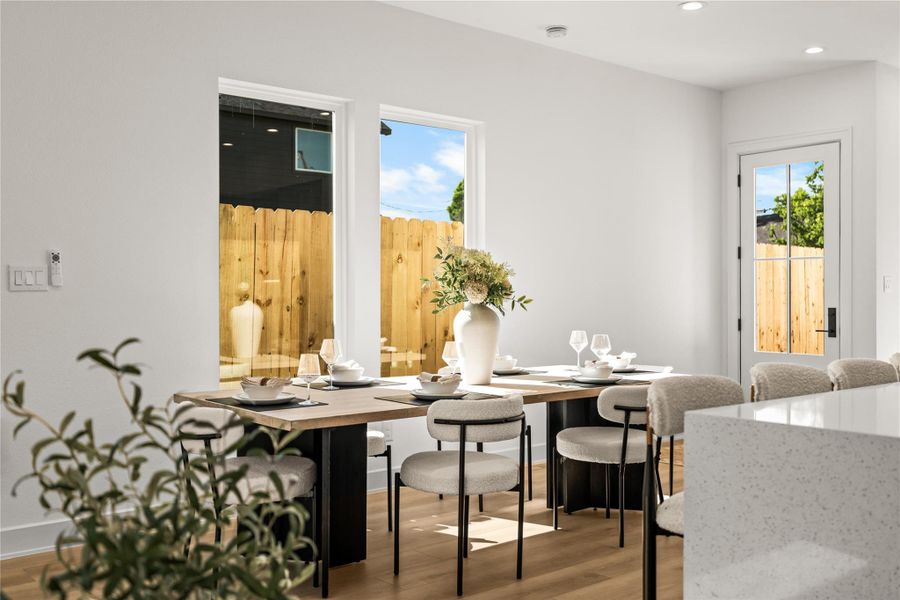 This bright dining area features two large windows that look out into the private, wood-fenced backyard. Light oak flooring runs throughout the space, leading directly to a glass back door that makes it easy to step outside.