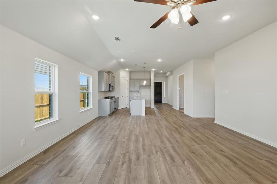 Unfurnished living room featuring light wood-style floors, baseboards, ceiling fan, and recessed lighting Unfurnished living room featuring light wood-style floors, baseboards, ceiling fan, and recessed lighting