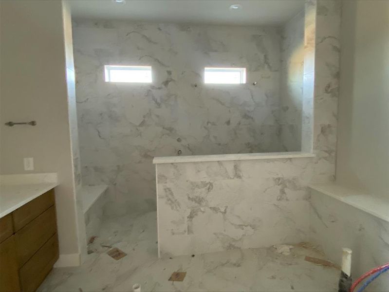 Full bathroom featuring a marble finish shower, vanity, and light marble finish flooring Full bathroom featuring a marble finish shower, vanity, and light marble finish flooring
