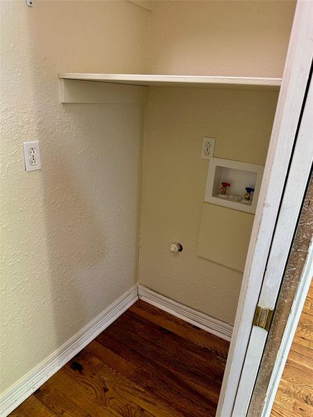 Laundry area with a textured wall, dark wood-style floors, and washer hookup