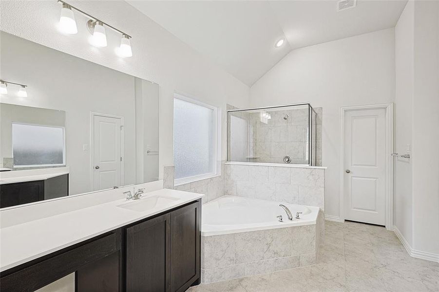 Bathroom with plus walk in shower, vanity, and vaulted ceiling