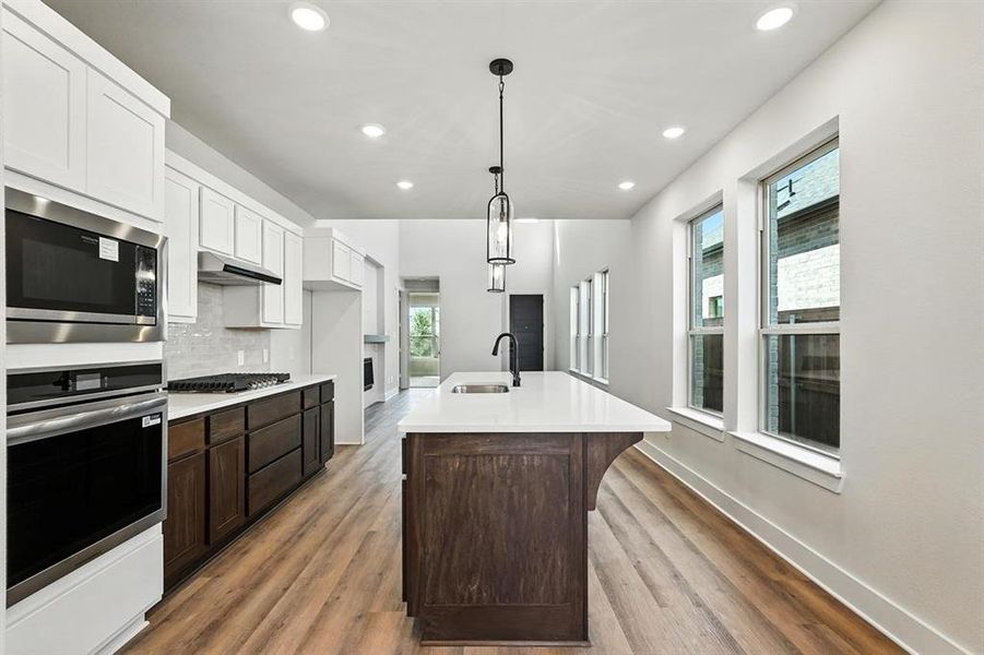 Kitchen featuring dark brown cabinetry, white cabinetry, recessed lighting, stainless steel appliances, and hanging light fixtures Kitchen featuring dark brown cabinetry, white cabinetry, recessed lighting, stainless steel appliances, and hanging light fixtures