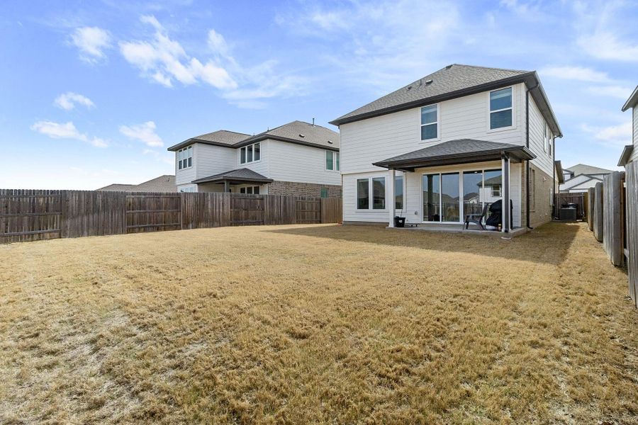 Back of house with  fenced lawn, and a patio