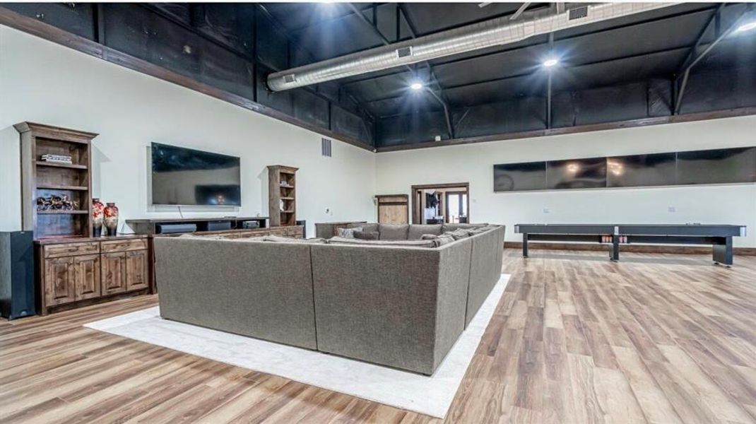 Living area with light wood-style flooring, a towering ceiling, and visible vents Living area with light wood-style flooring, a towering ceiling, and visible vents