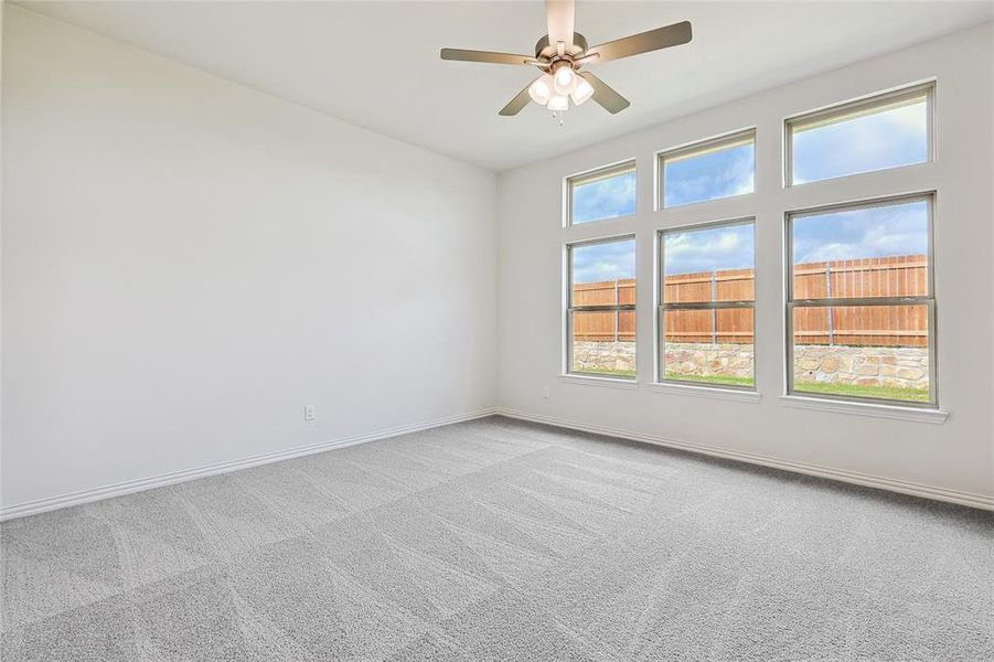 Carpeted empty room featuring ceiling fan and a healthy amount of sunlight