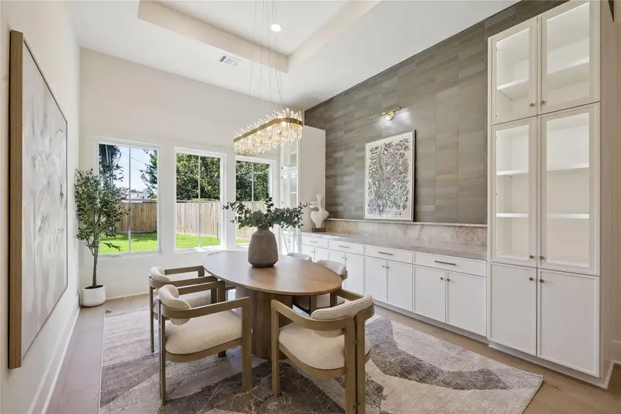 DINING ROOM: The spacious dining room is highlighted by custom built-in cabinetry with illuminated glass-front display cabinets, quartzite countertops, casement windows, and designer picture lighting.