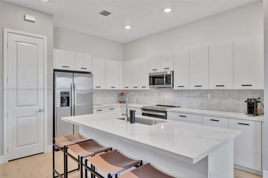 Kitchen w/ quart counters and counter seating, upgraded backsplash and handles. Pantry. Sink overlooks the great room