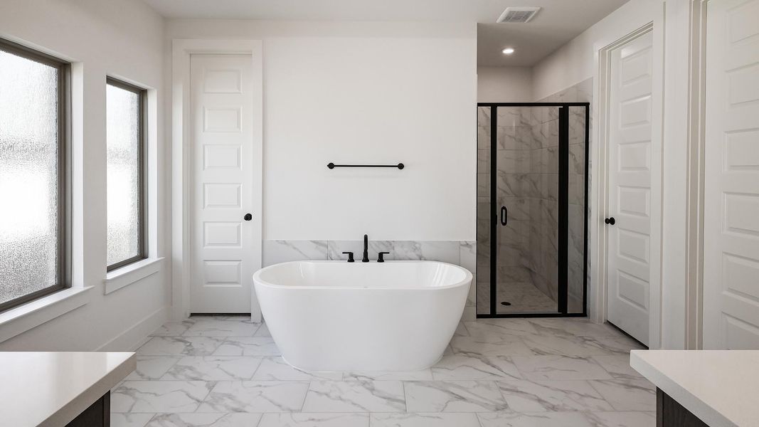 Full bath featuring a stall shower, marble finish floor, a freestanding bath, and vanity