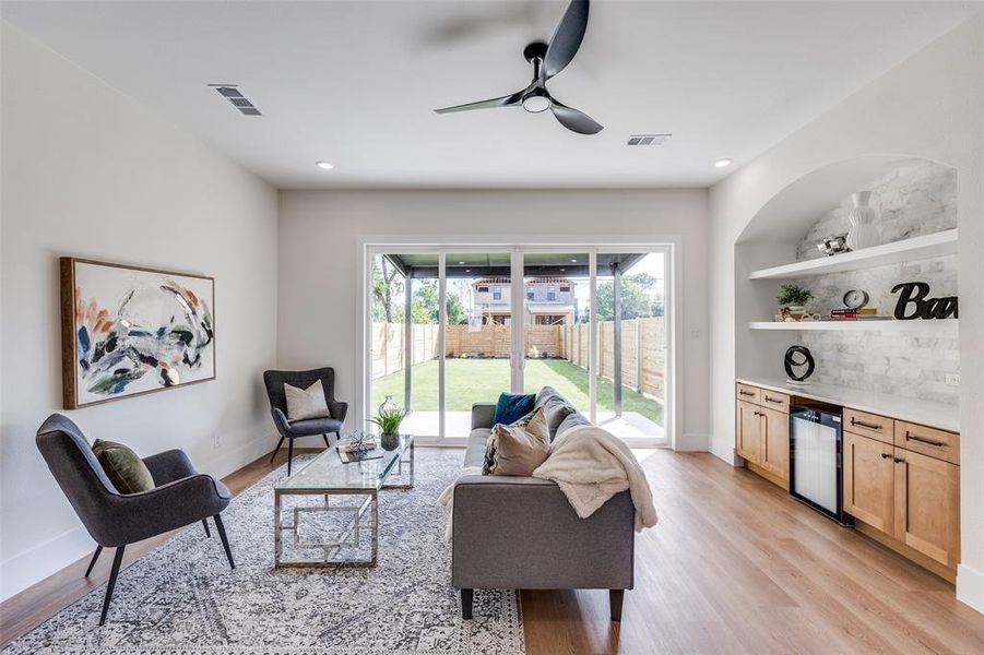 Living room featuring beverage cooler, a dry bar, light wood-style floors, a ceiling fan, and recessed lighting Living room featuring beverage cooler, a dry bar, light wood-style floors, a ceiling fan, and recessed lighting