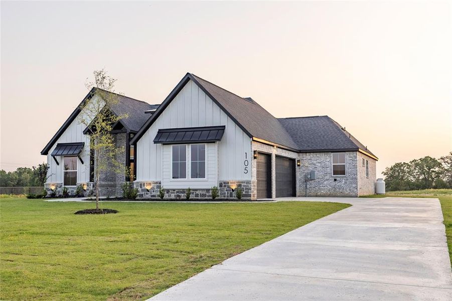 View of front of property with board and batten siding, a yard, concrete driveway, and an attached garage View of front of property with board and batten siding, a yard, concrete driveway, and an attached garage