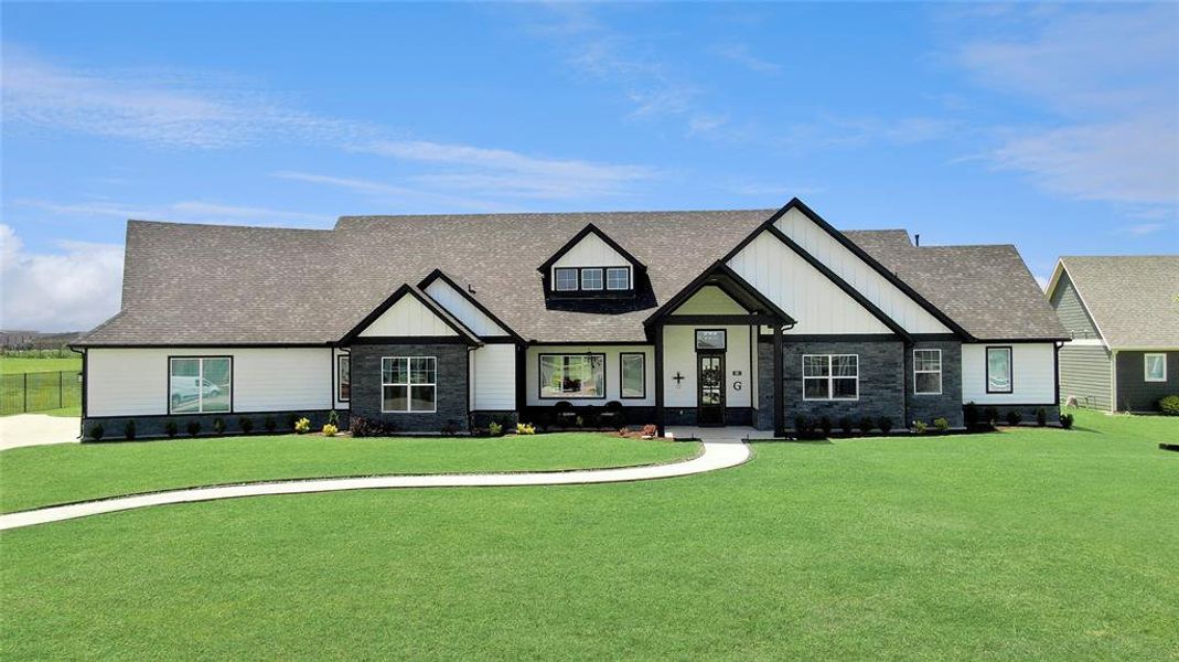 View of front of home featuring stone siding, a front lawn, a shingled roof, and board and batten siding View of front of home featuring stone siding, a front lawn, a shingled roof, and board and batten siding