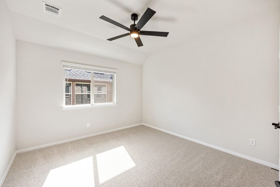 Empty bedroom with vaulted ceiling, black ceiling fan, carpet flooring, and a single window