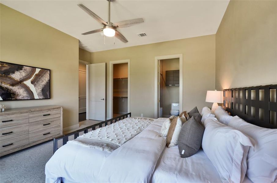 Bedroom featuring a spacious closet, ensuite bathroom, carpet, a closet, and a ceiling fan Bedroom featuring a spacious closet, ensuite bathroom, carpet, a closet, and a ceiling fan