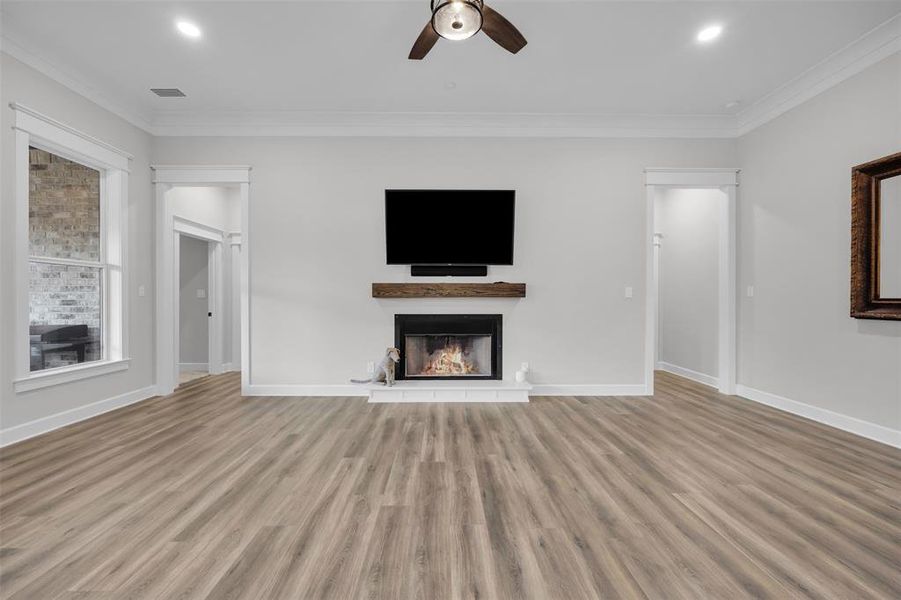 Unfurnished living room with plenty of natural light, light hardwood / wood-style flooring, ceiling fan, and ornamental molding