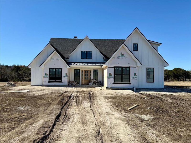 Modern farmhouse style home with covered porch, a standing seam roof, a shingled roof, and board and batten siding