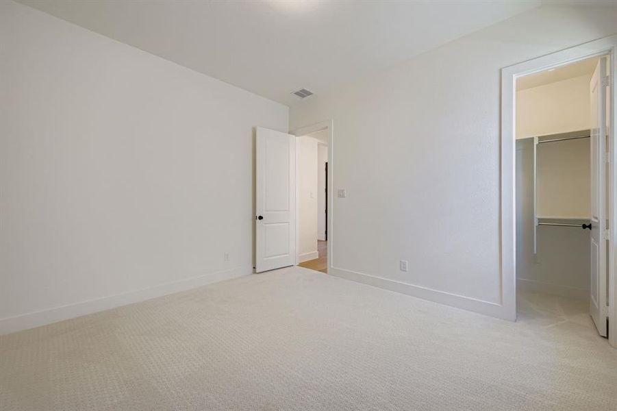 Unfurnished bedroom featuring a spacious closet and light colored carpet Unfurnished bedroom featuring a spacious closet and light colored carpet