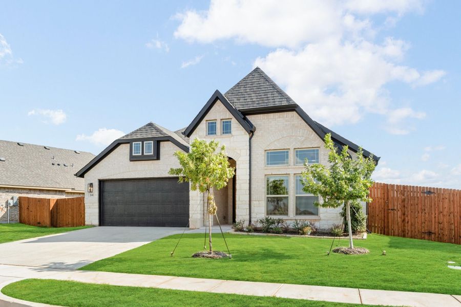 Single-story home with light stone exterior, dark roof, two-car garage, and green front lawn with young trees