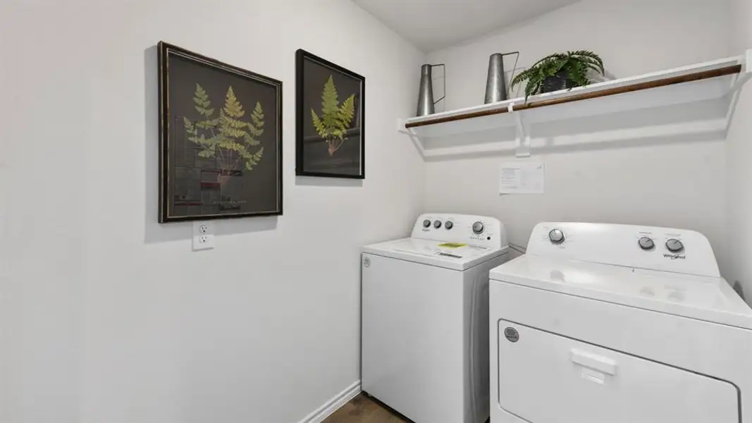 Dedicated laundry area featuring white washer and dryer units, a wall-mounted white shelf with a hanging rod, and light-toned walls Dedicated laundry area featuring white washer and dryer units, a wall-mounted white shelf with a hanging rod, and light-toned walls