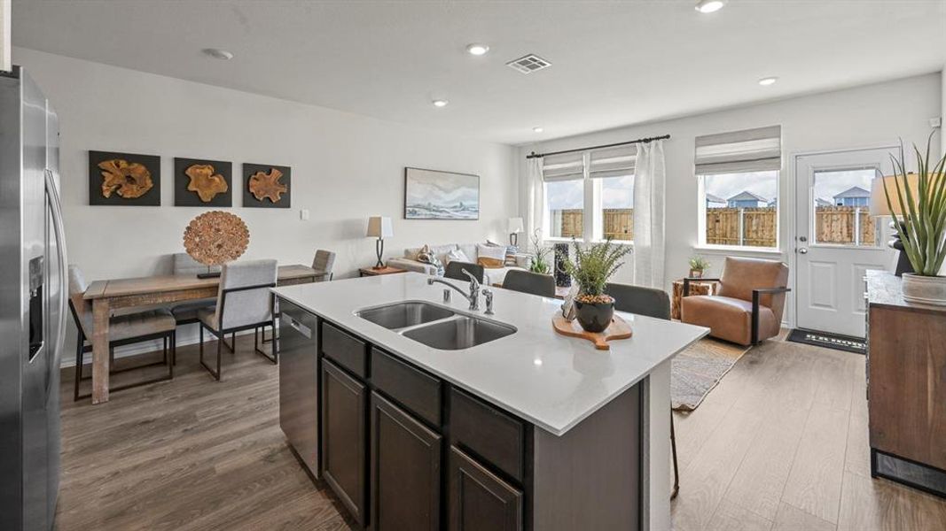 Kitchen featuring open floor plan, stainless steel appliances, dark wood-type flooring, recessed lighting, and an island with sink