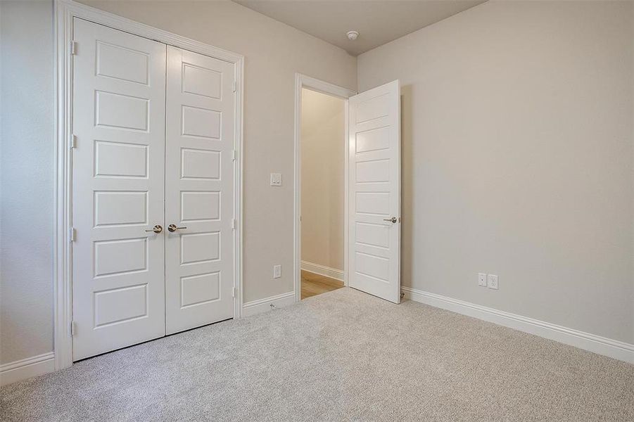 Unfurnished bedroom featuring light carpet and a closet