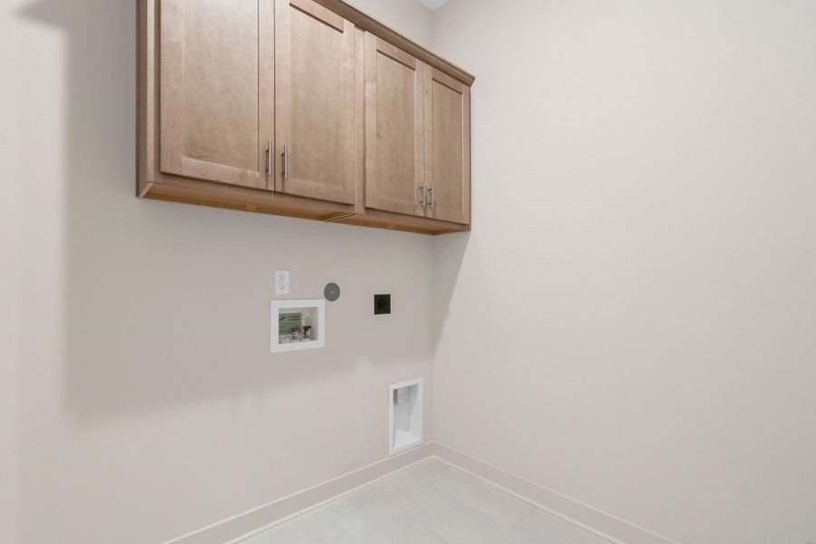 Laundry space featuring light wood-finish cabinetry, neutral wall tones, and light-toned floor tile Laundry space featuring light wood-finish cabinetry, neutral wall tones, and light-toned floor tile